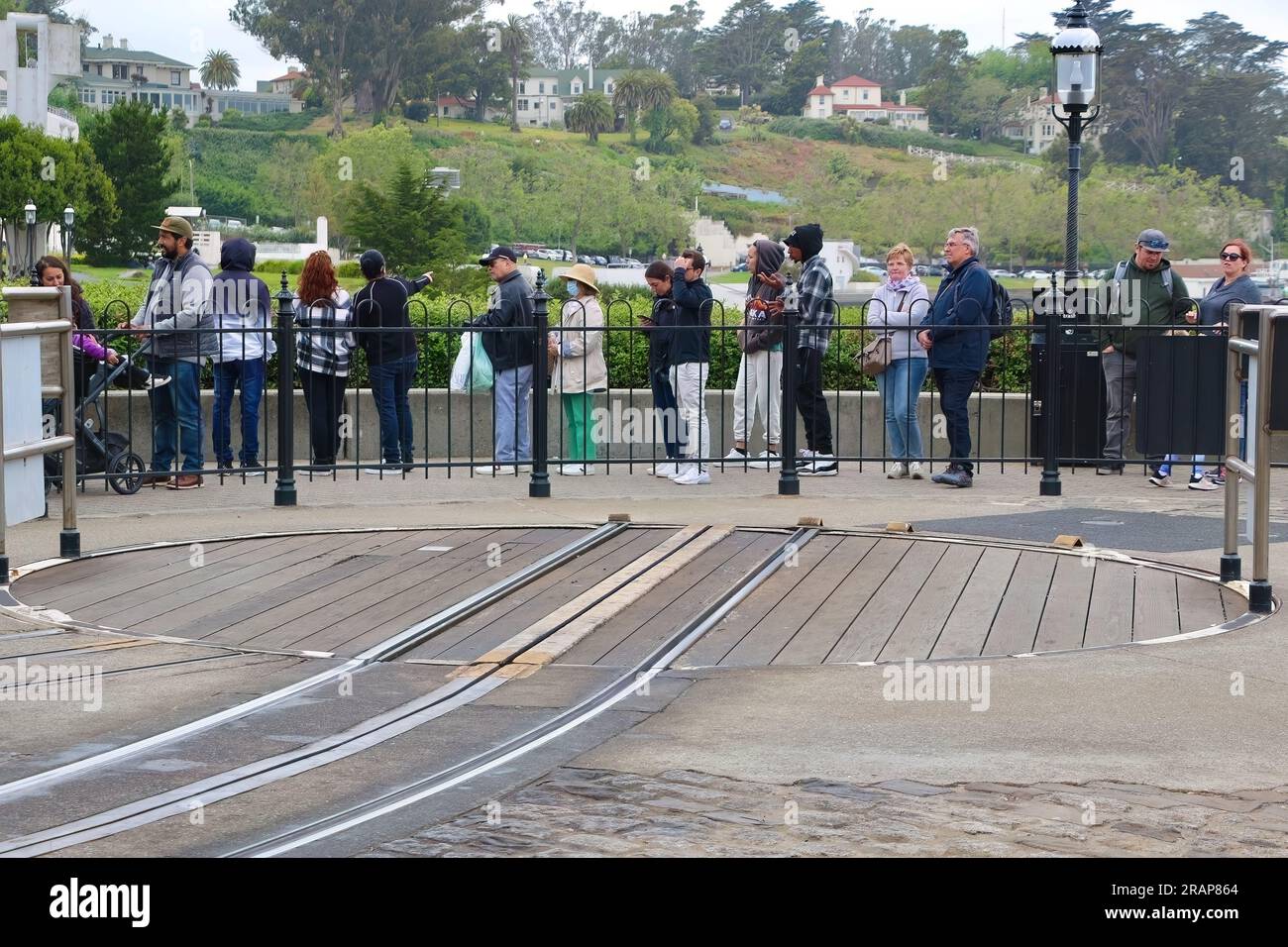 Touristen warten an einem kalten Tag im Mai in San Francisco Kalifornien USA in der Warteschlange am Hyde and Beach Cable Car Terminal mit einer leeren Drehscheibe Stockfoto