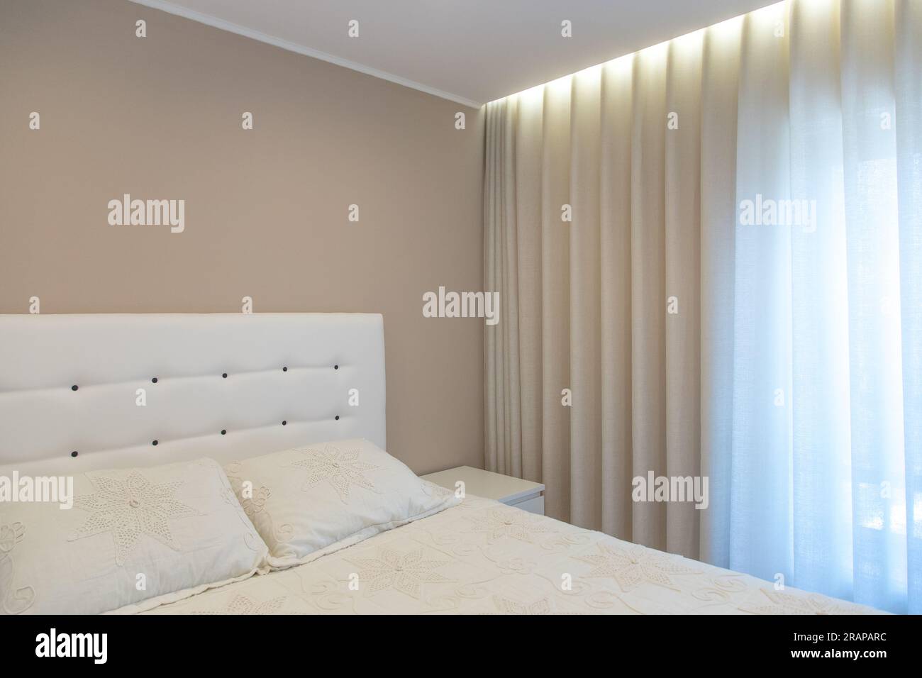 Detail des Innenraums eines hellen Zimmers mit Kissen, Kopfteil, Vorhang und Decke, sehr komfortabel, gemütlich und modern Stockfoto