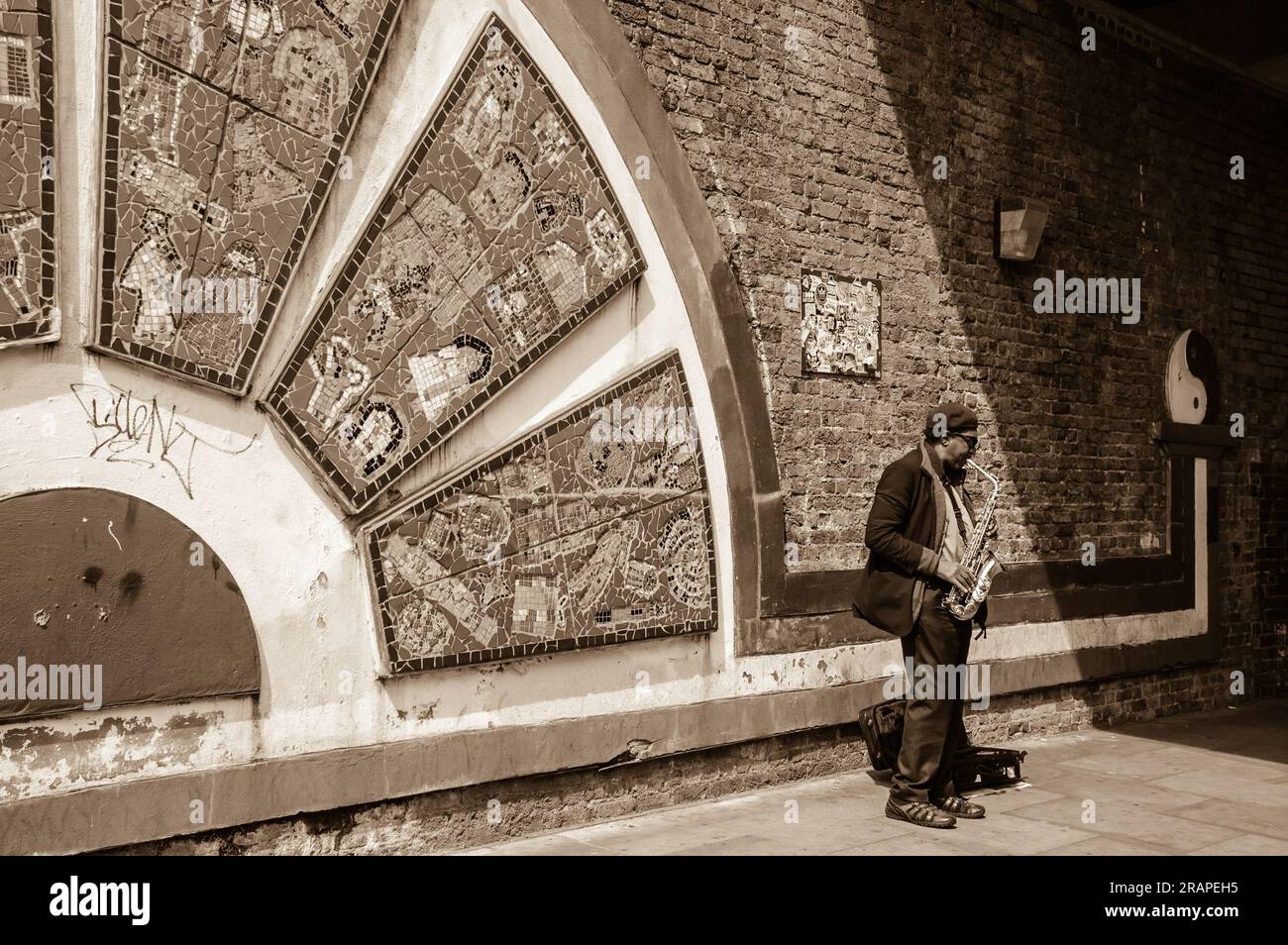 LONDON, ENGLAND, Großbritannien - 4. MAI 2014: Unbekannter Saxophonspieler auf dem Brick Lane Market. Dutzende Straßenmusiker treten auf den Straßen Londons auf. Sepia-Foto Stockfoto