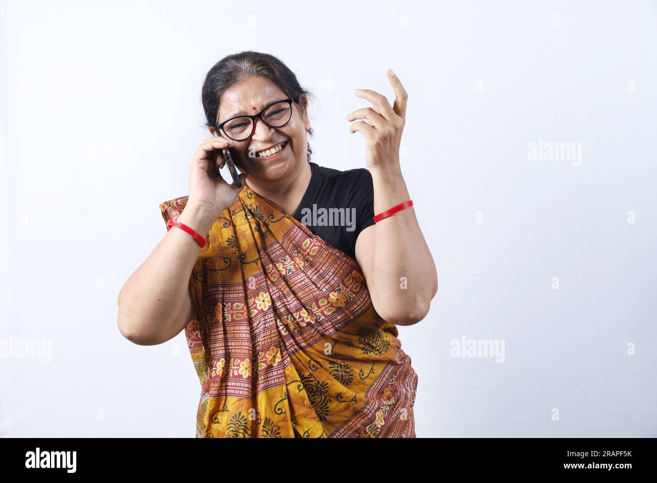 Ländliche indische alte Frau, die Saree trägt und verschiedene Ausdrücke am Telefon darstellt. Sie hat ein Handy in der Hand. GoDigital-Konzept im ländlichen Indien. Stockfoto