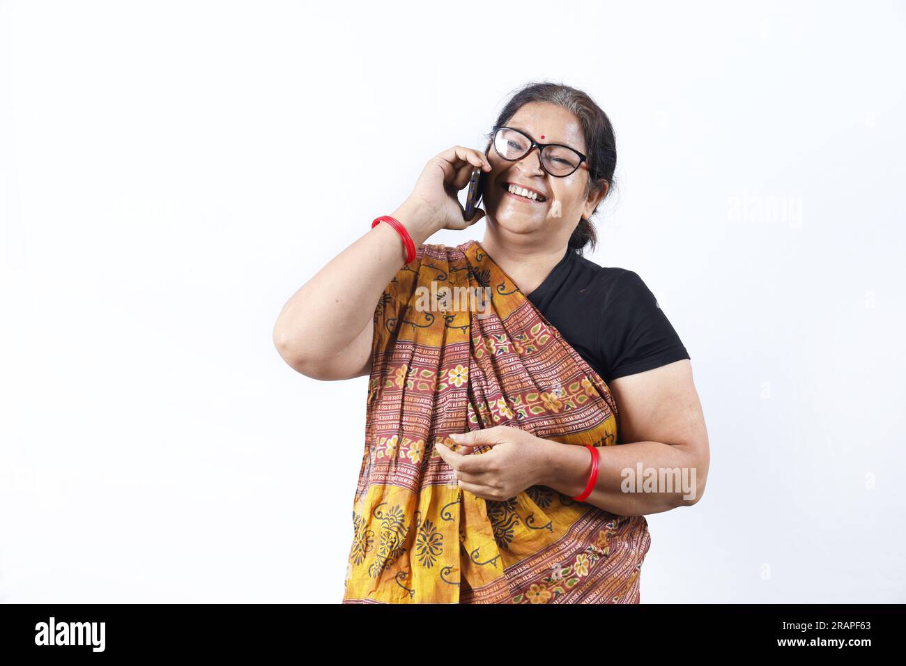 Ländliche indische alte Frau, die Saree trägt und verschiedene Ausdrücke am Telefon darstellt. Sie hat ein Handy in der Hand. GoDigital-Konzept im ländlichen Indien. Stockfoto