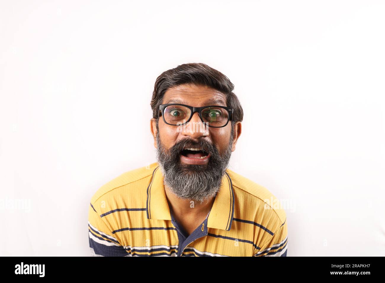 Porträt eines bärtigen Indianers mit Brille und T-Shirt. Seltsame Ausdrücke verzerrten das Gesicht. Ein betäubter Mann, der verschiedene Stimmungen von verrückter Persönlichkeit zeigt. Stockfoto