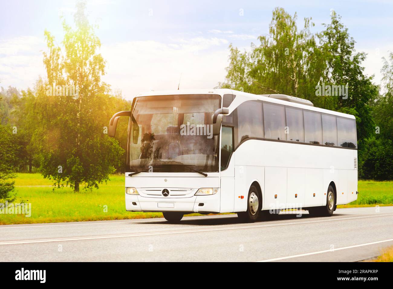 Weißer Mercedes-Benz Tourismo-Bus mit hoher Geschwindigkeit auf der Straße im goldenen Sonnenlicht des Sommers. Salo, Finnland. 22. Juni 2023. Stockfoto