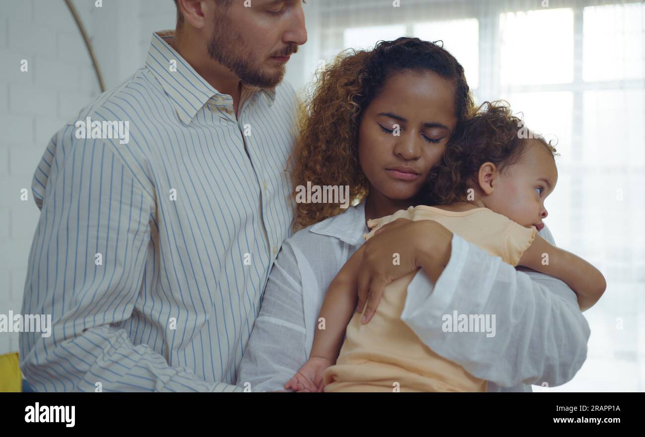 Eltern und ihre charmante kleine Tochter sind zu Hause beruhigend und umarmen sich. Stockfoto