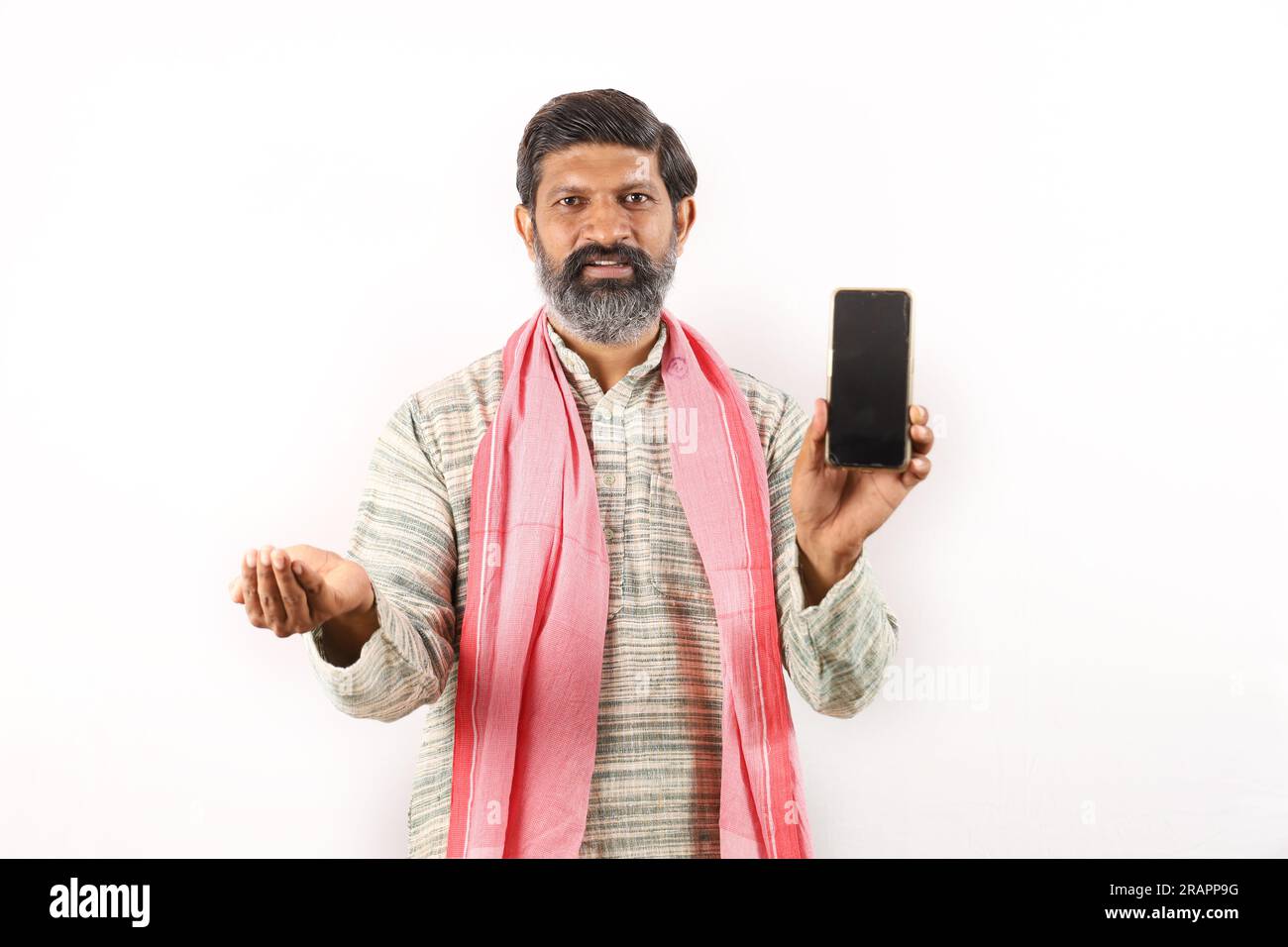 Fröhlicher Landwirt, der den Bildschirm des Mobiltelefons zeigt und Technologie verwendet. Samen in der anderen Hand. Glücklicher indischer bärtiger Bauer im ländlichen Indien Konzept. Stockfoto