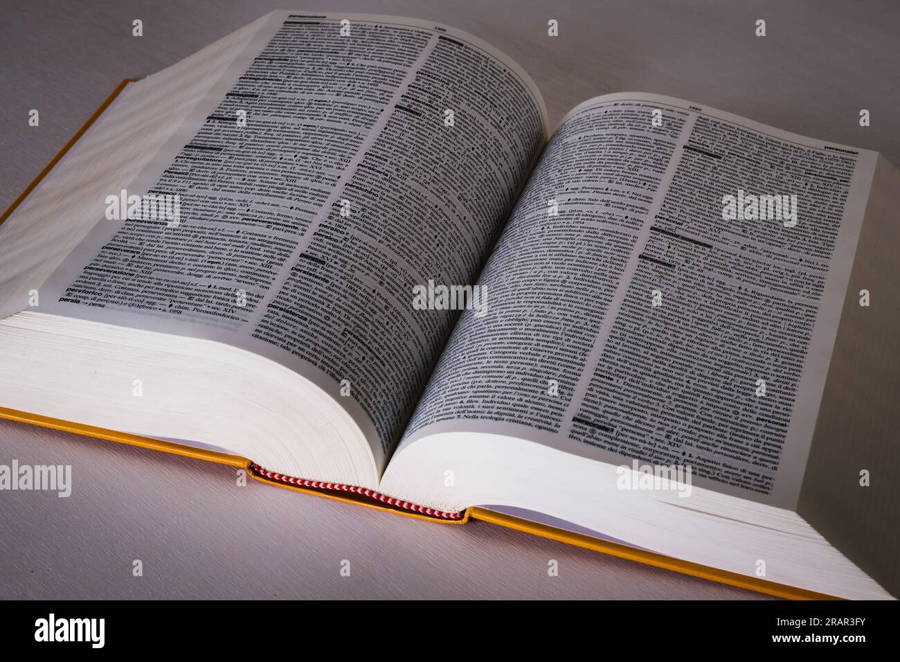 Wörterbuch mit Tausenden von Seiten in einer weißen Tabelle geöffnet. Stockfoto