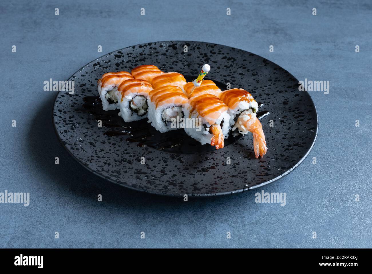 Sushi Restaurant, Uramaki Tiger serviert auf einem runden schwarzen Teller. Stockfoto
