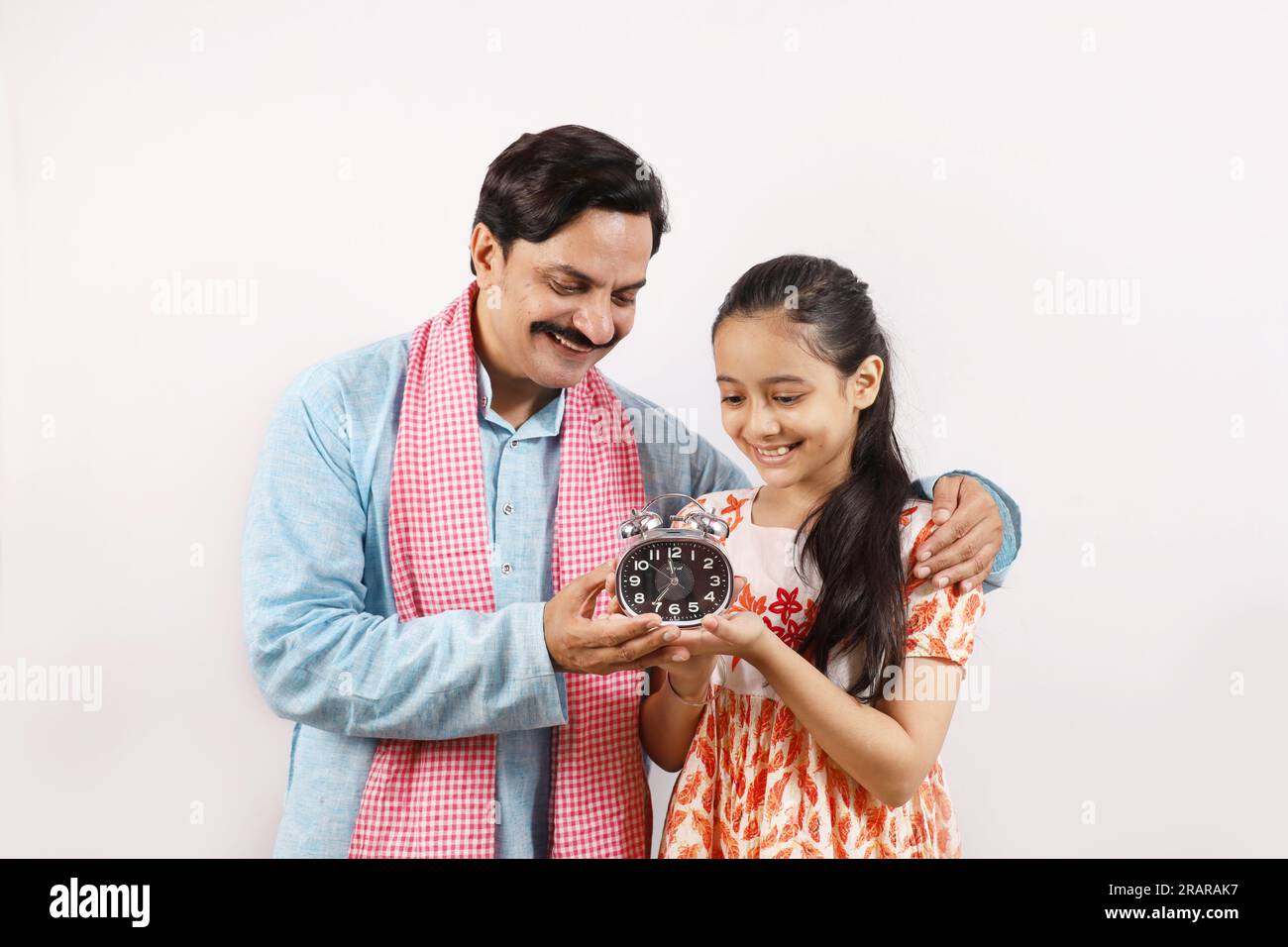 Ein indischer Landvater, der seiner Teenager-Tochter die Bedeutung von Zeit und diszipliniertem Leben erklärt. Stockfoto
