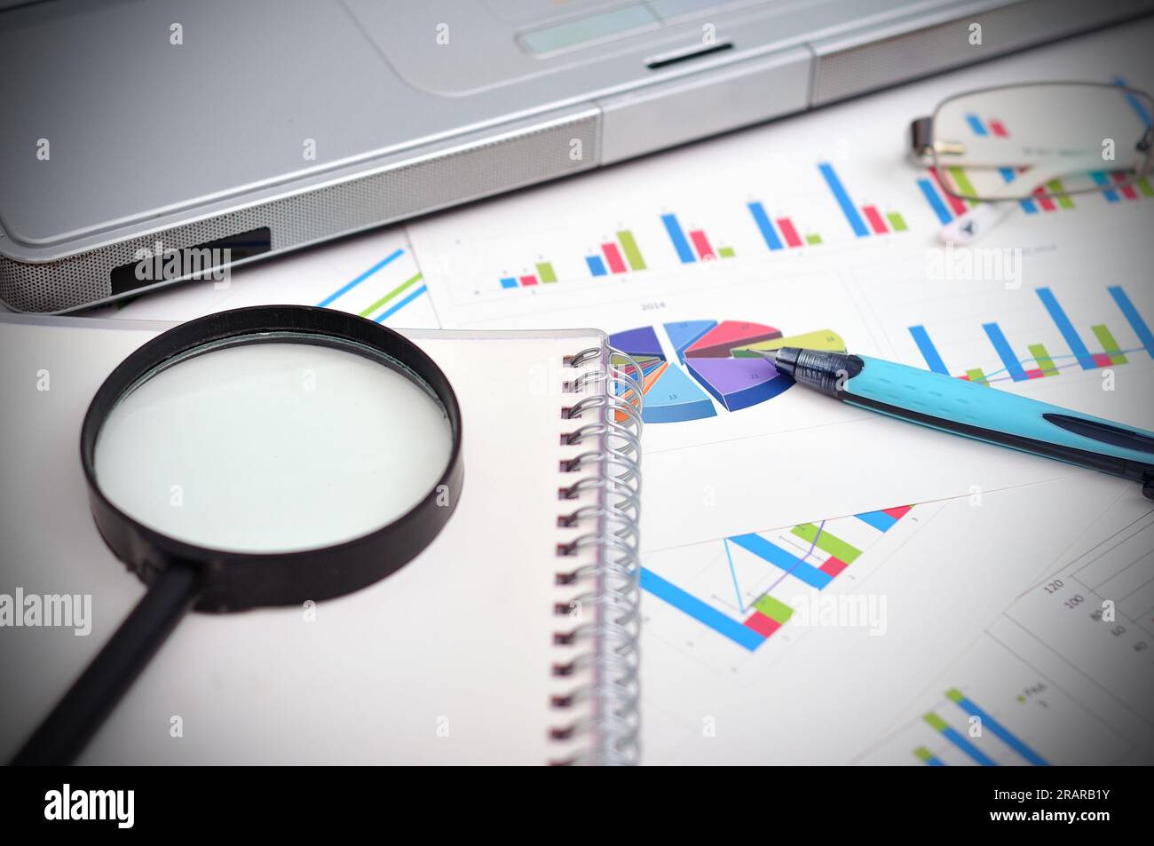 Marktanalysekonzept mit Finanzbericht, Stift, Laptop und Lupe Stockfoto