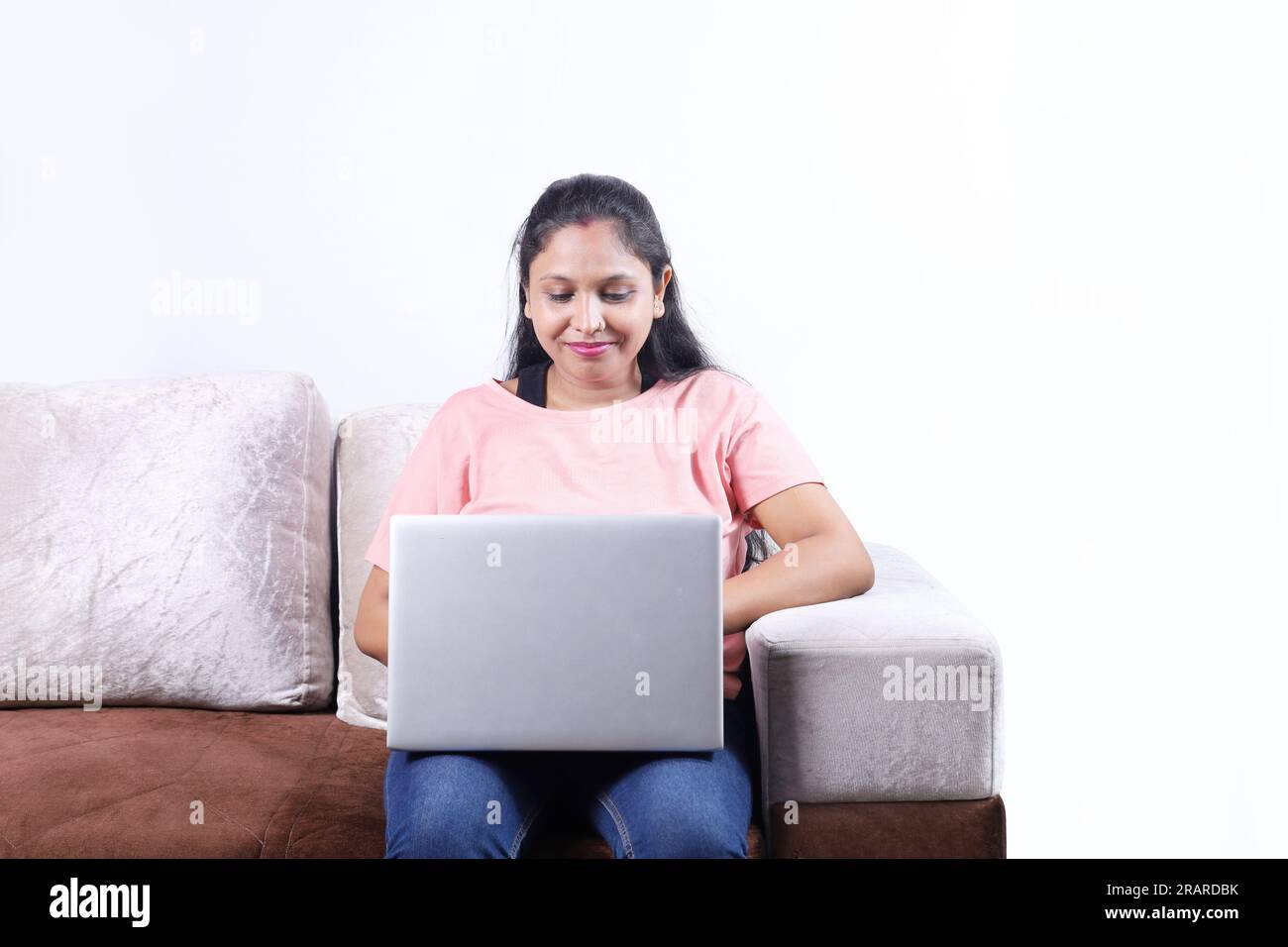 Glückliche indische Familie von Vater, Mutter, Sohn und Tochter, die mit dem Laptop surfen und eine angenehme Zeit zusammen verbringen. Die Familie schaut sich das Notebook an. Stockfoto