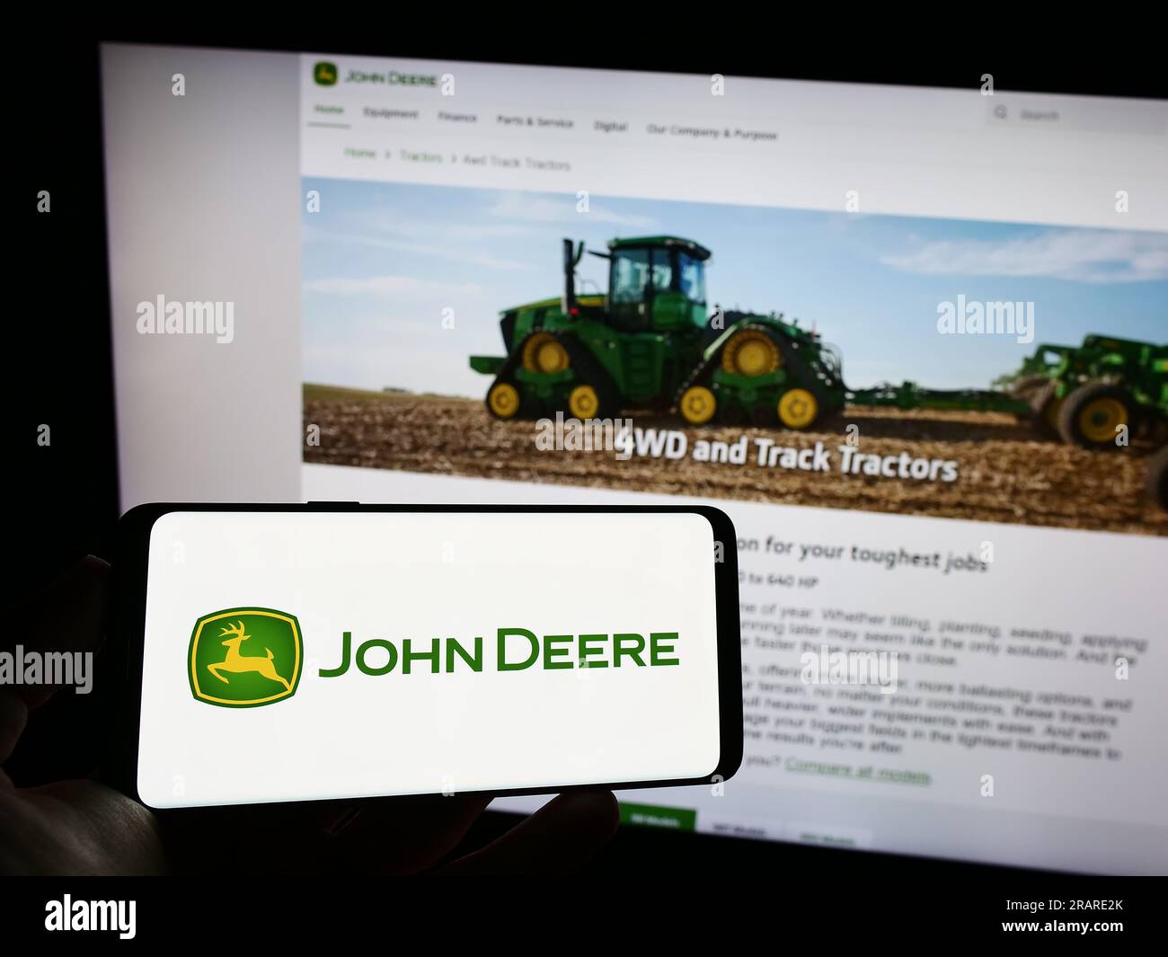 Person, die ein Mobiltelefon mit dem Logo des US-amerikanischen Unternehmens Deere and Company (John Deere) auf dem Bildschirm vor der geschäftlichen Webseite hält. Konzentrieren Sie sich auf das Display des Telefons. Stockfoto