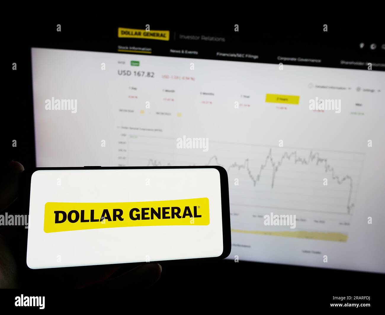 Person, die ein Mobiltelefon mit dem Logo des US-Einzelhandelsunternehmens Dollar General Corporation auf dem Bildschirm vor der Webseite hält. Konzentrieren Sie sich auf das Display des Telefons. Stockfoto