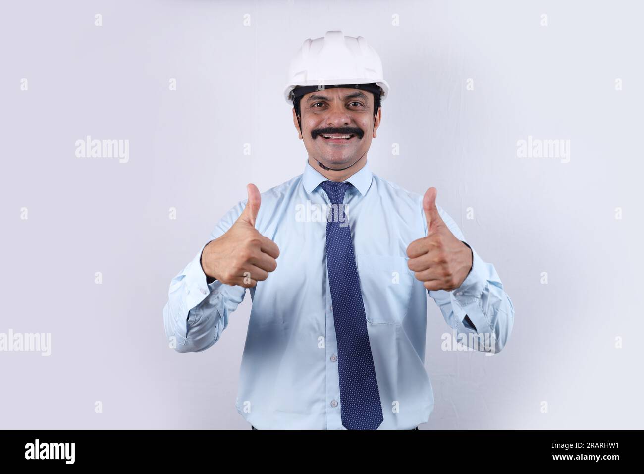 Bauarbeiter, die Daumen hoch für eine bessere Zukunft. Der fröhliche Ingenieur trägt einen technischen Helm. Stockfoto
