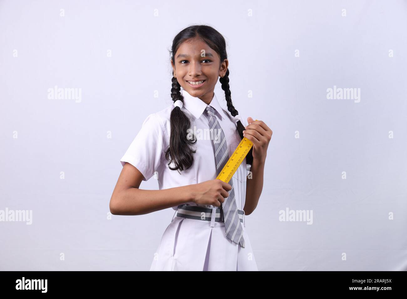 Ein indisches Landstadtmädchen, das ein Bildungskonzept macht und sich darauf vorbereitet, in Zukunft erfolgreich zu werden. Das Mädchen, das eine Waage als Klassenmonitor hält. Stockfoto