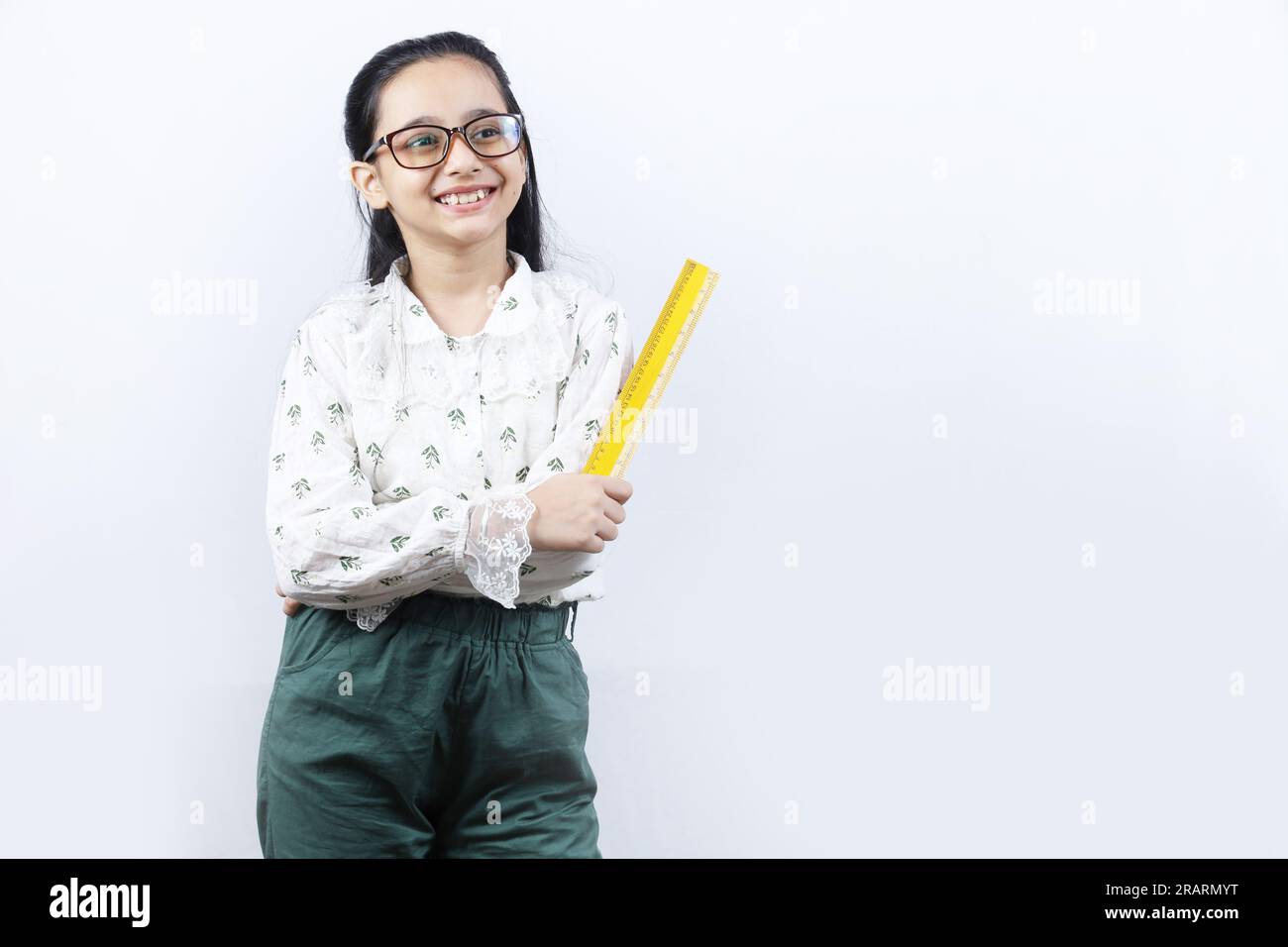 Junge Lehrerin. Porträt eines glücklichen indischen Teenagers, das eine Messskala in der Hand hält und eine Brille trägt. Monitorkonzept der jungen Klasse. Stockfoto