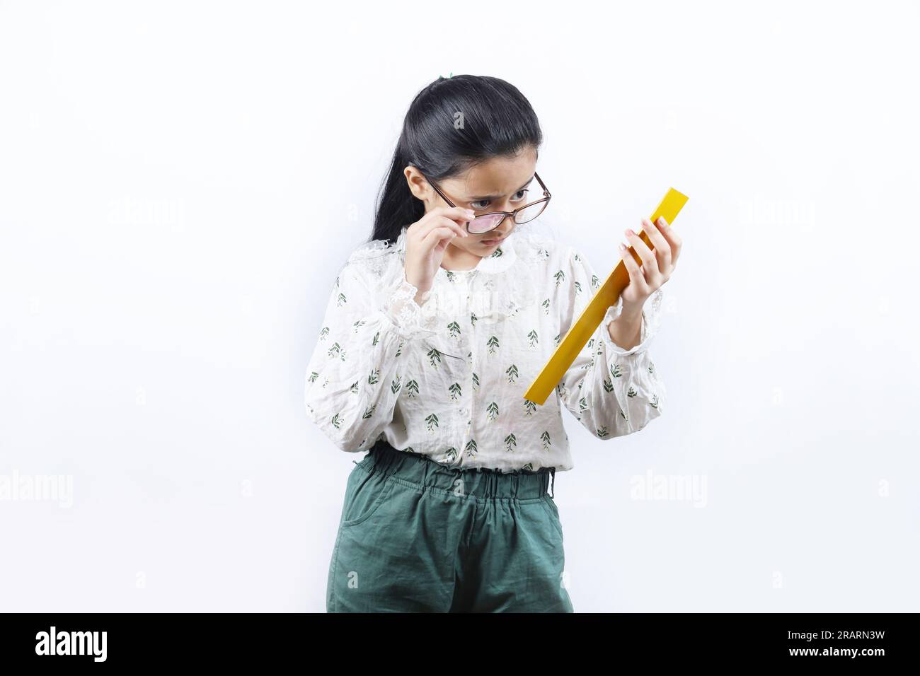 Junge Lehrerin. Porträt eines glücklichen indischen Teenagers, das eine Messskala in der Hand hält und eine Brille trägt. Monitorkonzept der jungen Klasse. Stockfoto