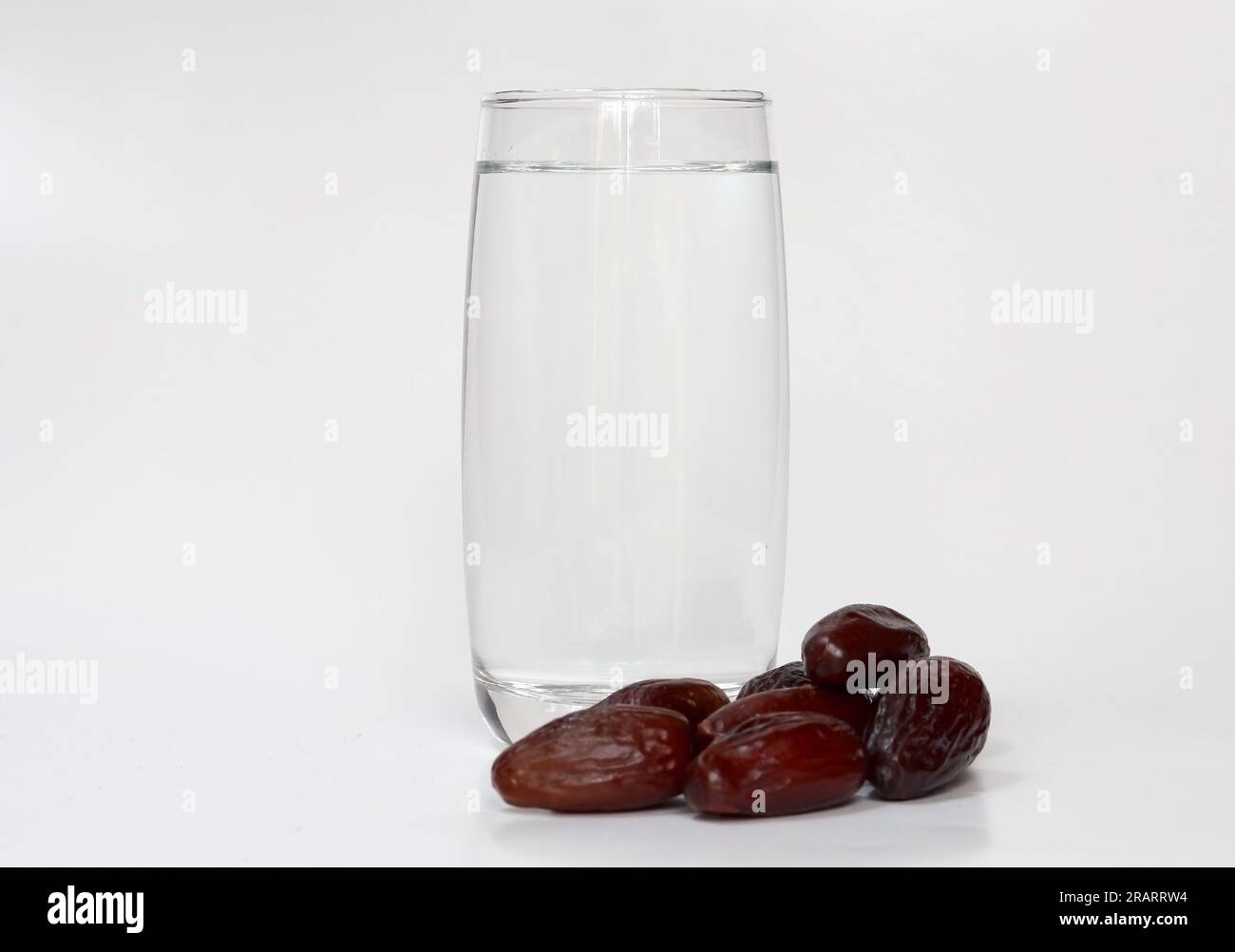 Glas Wasser und Dattelfrucht isoliert auf weißem Hintergrund. Moslems brechen das Fasten mit Wasser und Datteln Obst Stockfoto