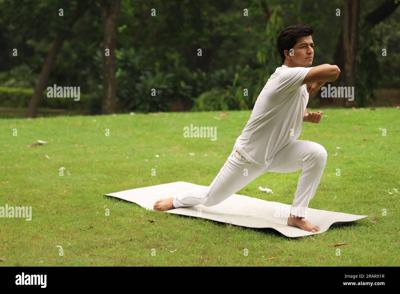 Junger Junge beim Sport und Yoga posieren in grüner, ruhiger Umgebung am frühen Morgen im Park, um einen gesunden Lebensstil zu erhalten. Internationaler Yoga-Tag. Stockfoto