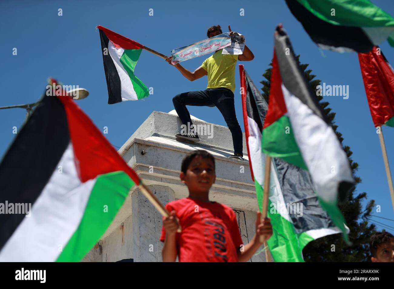 Während einer Demonstration in Gaza-Stadt, bei der gegen eine israelische Militäroperation im besetzten Westjordanland protestiert wurde, heben Palästinenser nationale Flaggen und Plakate. Israel hat seine Einsätze im nördlichen Westjordanland, in dem die Stadt Dschenin und das angrenzende Flüchtlingslager untergebracht sind, verstärkt. Gaza-Stadt, Palästina. Stockfoto