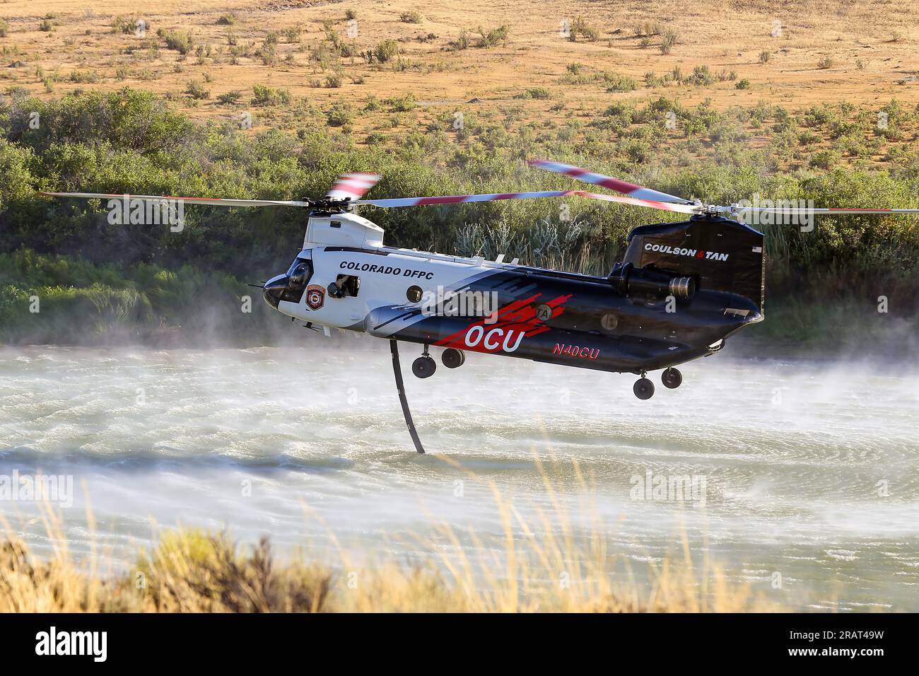 Ein Chinook-Hubschrauber, der dem North Blue Fire etwa 10 Meilen östlich von Jensen, Utah, zugeteilt wurde, entzieht am 11. August 2022 Wasser aus dem Green River vor dem Dinosaur National Monument. Das nordblaue Feuer wurde durch Blitze verursacht. Stockfoto