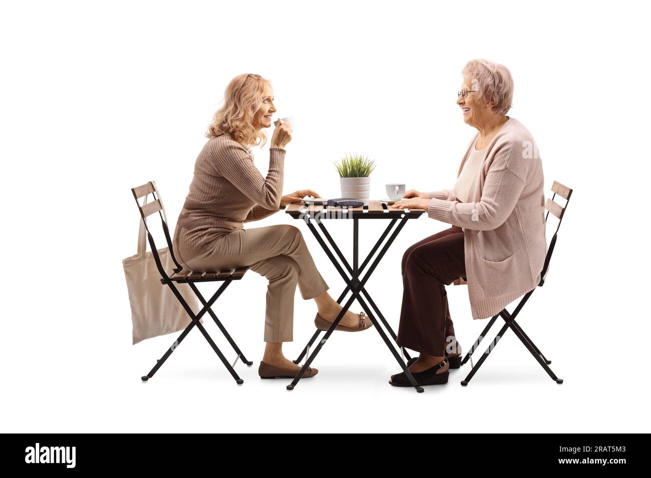 Ältere Mutter mit Tochter, die an einem Tisch sitzt und Kaffee trinkt, isoliert auf weißem Hintergrund Stockfoto