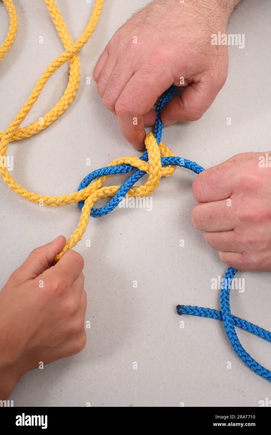 Die Hände binden das farbige Seil in Knoten Stockfoto