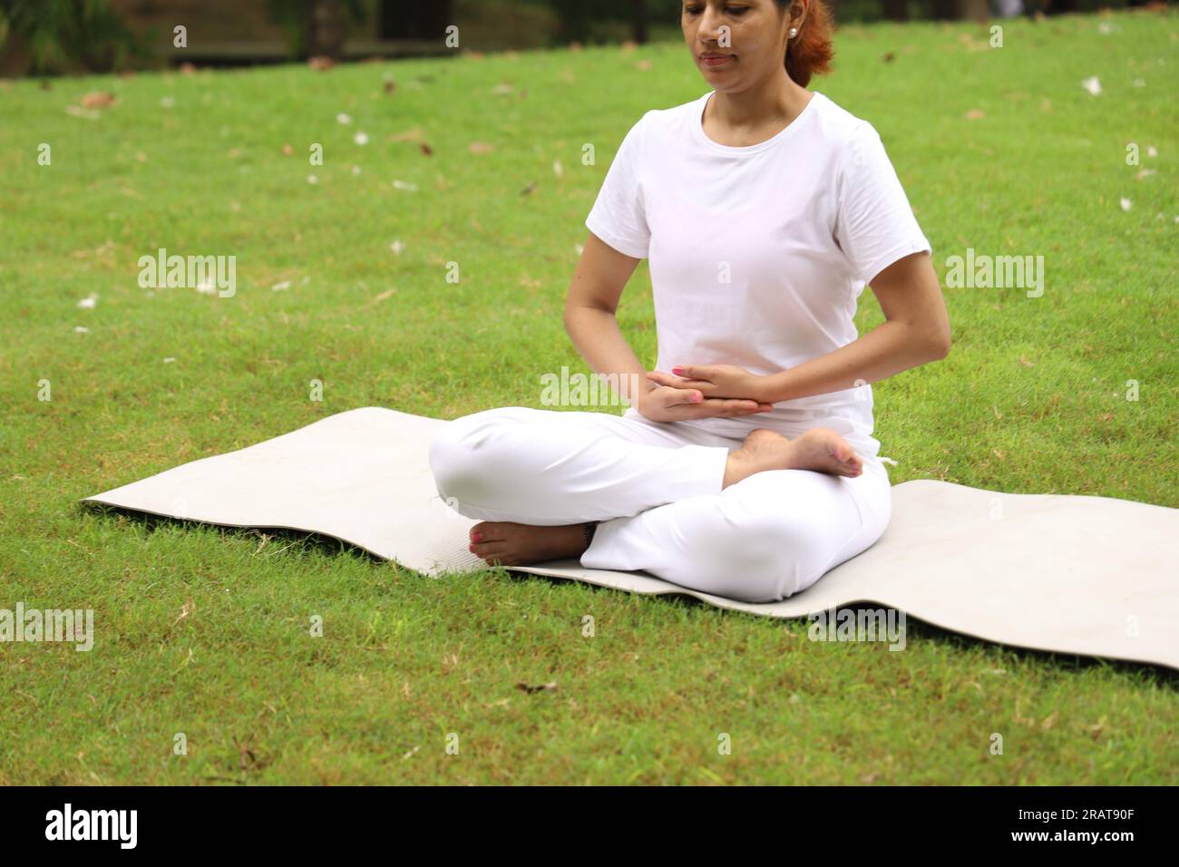 Schlanke Frau, die Yoga macht und macht, posiert in grüner, ruhiger Umgebung am frühen Morgen im Park, um einen gesunden Lebensstil aufrechtzuerhalten. Internationaler Yoga-Tag. Stockfoto