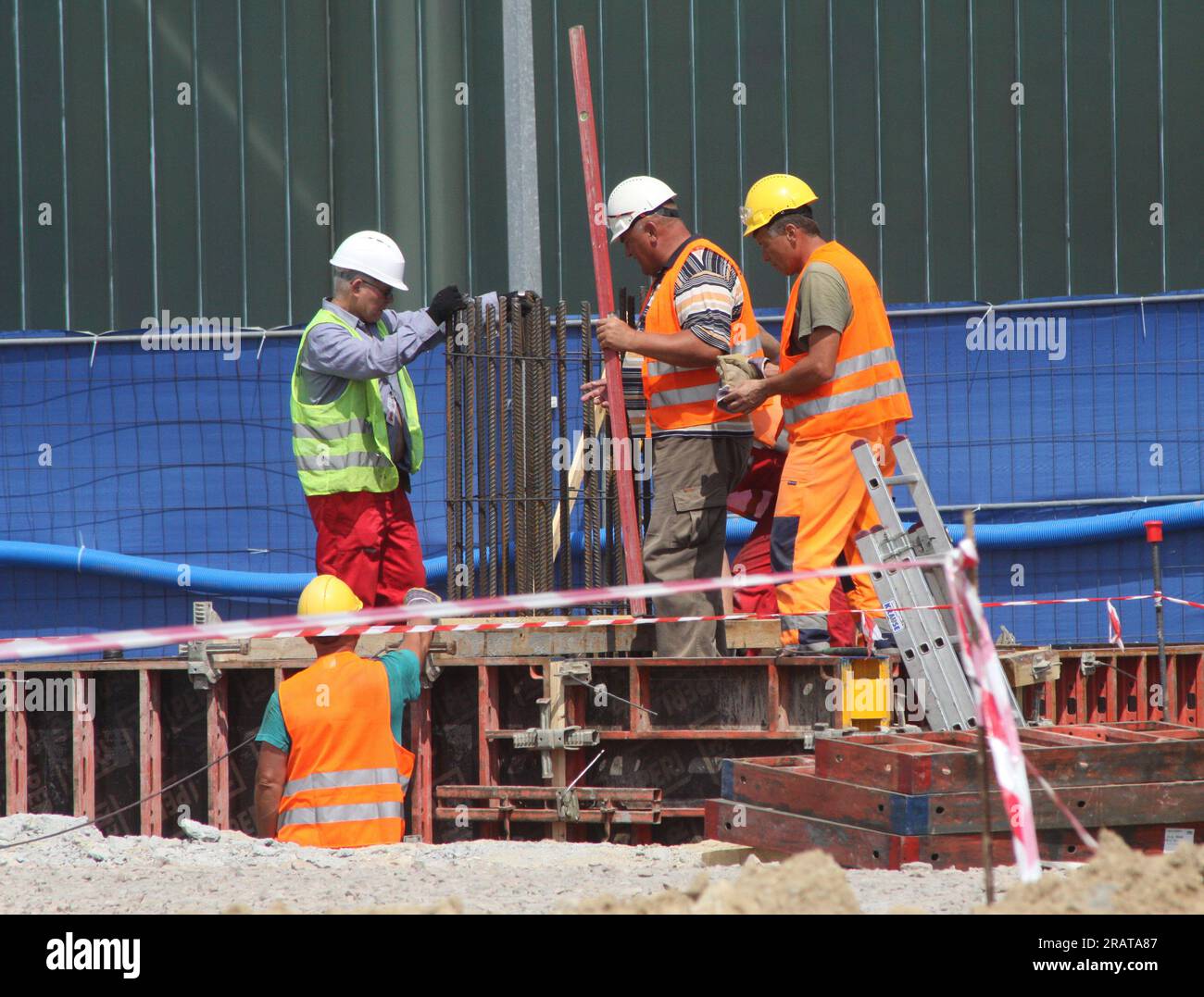 Gruppe von Arbeitern, die Stahlverstärkungen auf der Baustelle montieren. Stockfoto