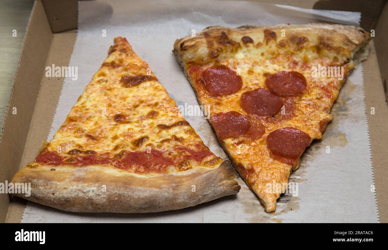 New yorker Pizzastück (Pepperoni, einfache Scheibe) nyc-Pizzeria mit zerdrückten roten Pfefferflocken auf fettigem Pergamentpapier, Pappschachtel Stockfoto