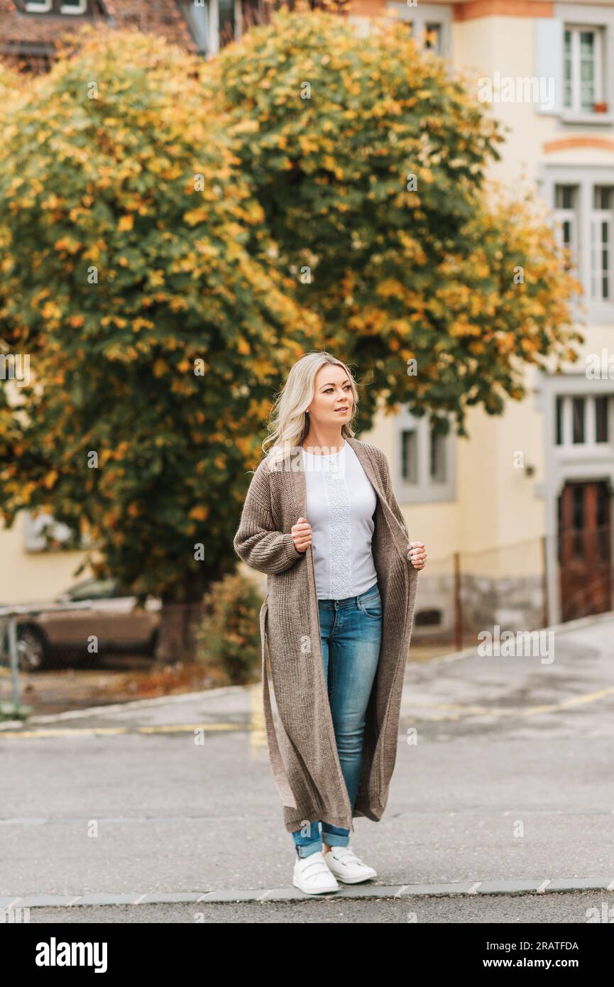 Außenporträt einer Modefrau mit langer beigefarbener Strickjacke Stockfoto