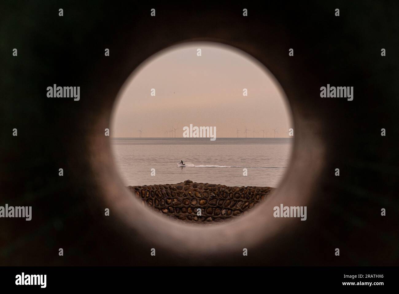 Ein Jetski, der durch das Loch einer riesigen Doughnut-Kunststatue an Brightons Uferpromenade gesehen wird Stockfoto