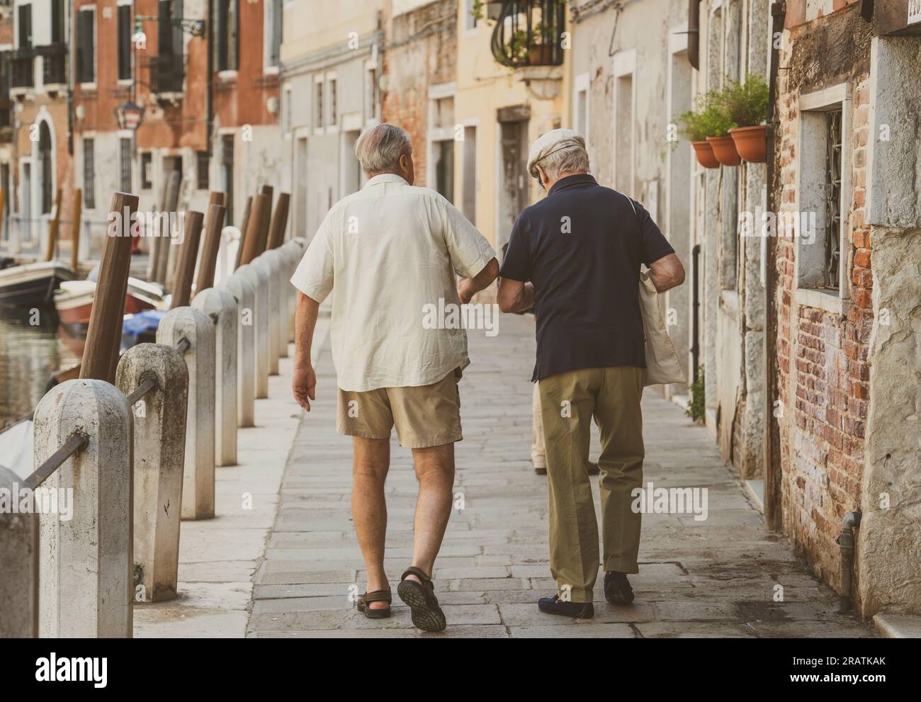 Zwei italienische Senioren laufen auf den kopfsteingepflasterten engen Gassen in Venedig, Italien Stockfoto