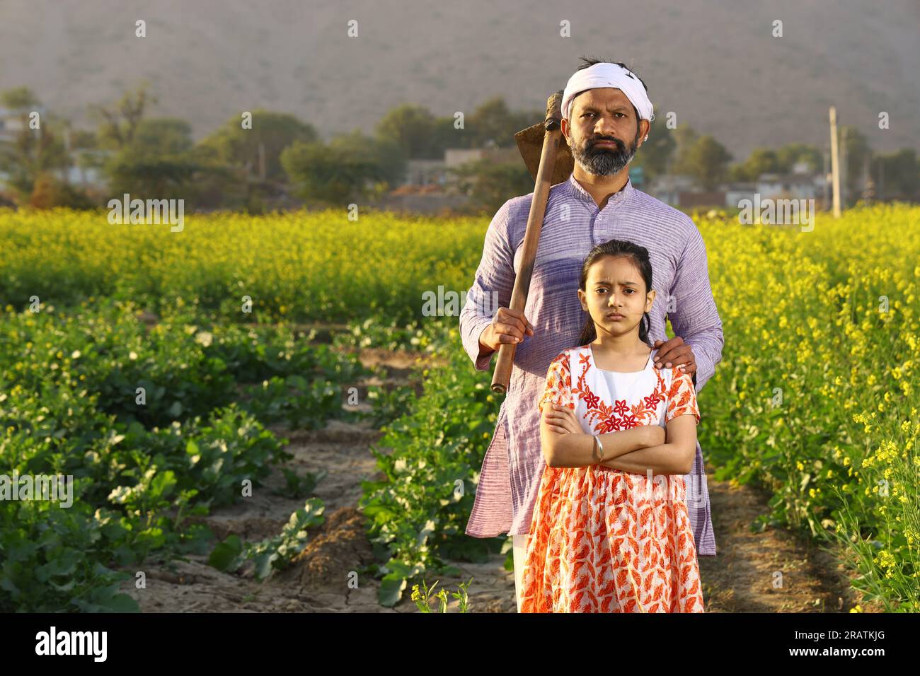 Wunderschönes dramatisches Porträt eines wütenden indischen Bauern und einer Tochter, die auf dem Senffeld mit Kurta-Pyjama und Schaufel in der Hand stand. Stockfoto
