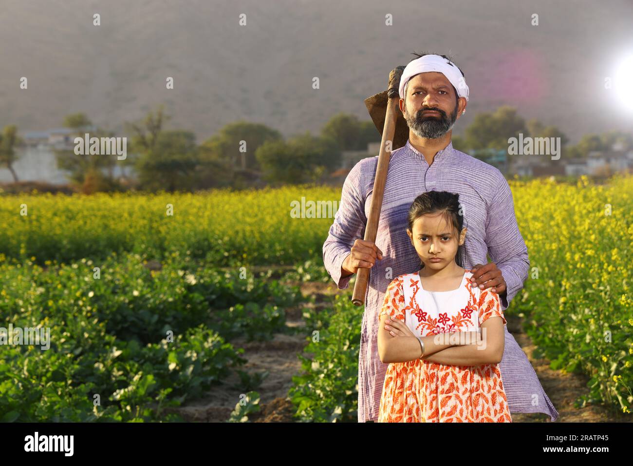 Wunderschönes dramatisches Porträt eines wütenden indischen Bauern und einer Tochter, die auf dem Senffeld mit Kurta-Pyjama und Schaufel in der Hand stand. Stockfoto