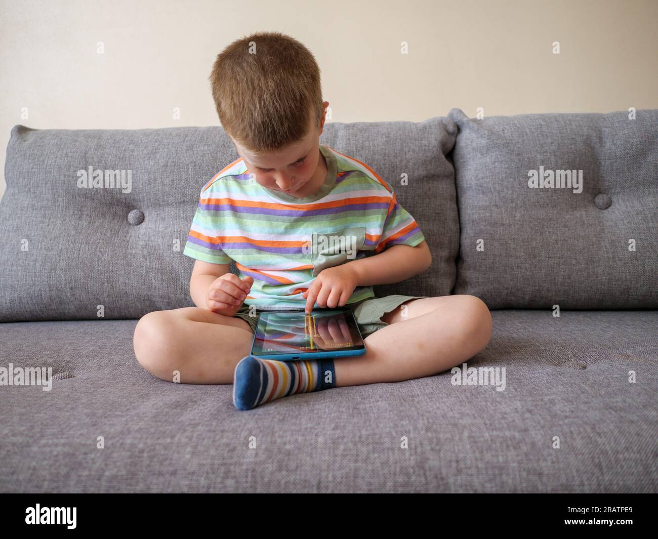 Kleines, vierjähriges Kind, das zu Hause auf einem Tablet spielt Stockfoto