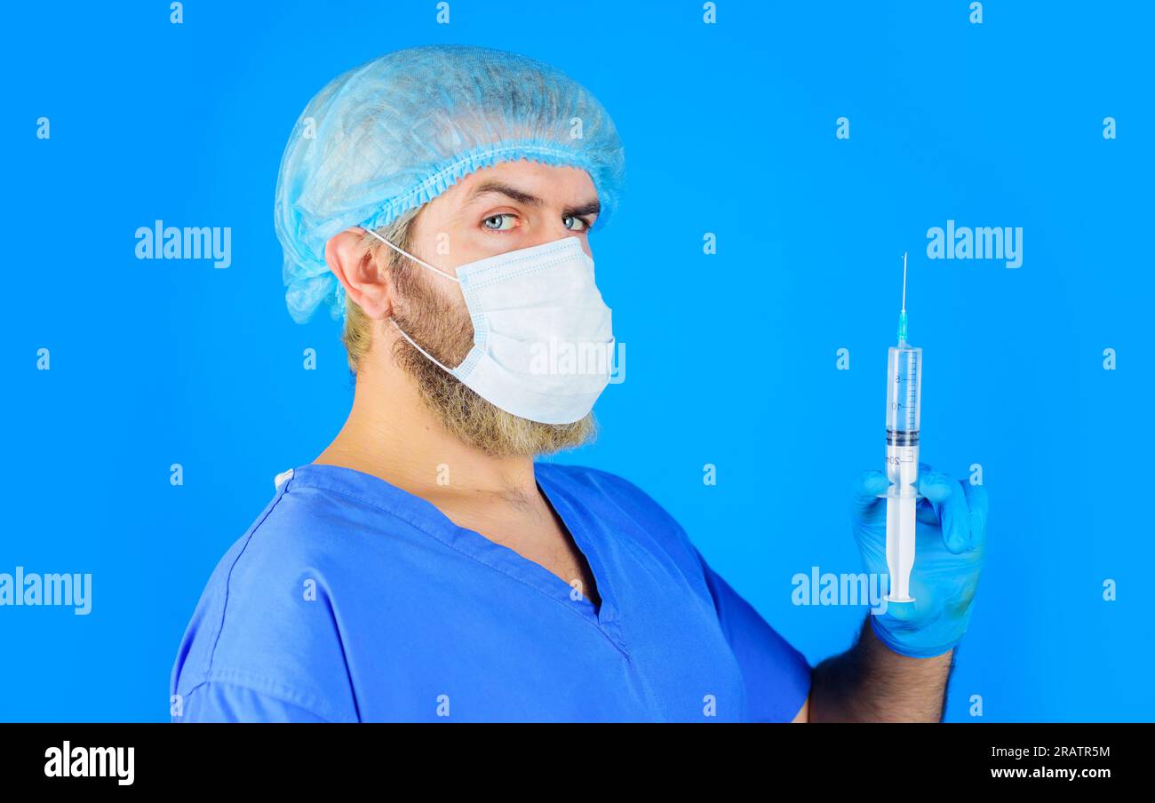 Arzt in medizinischer Maske mit Spritze in der Hand. Krankenhauspersonal. Arzt mit Spritze bereitet die Injektion vor. Krankenschwester in Uniform und Gummihandschuhe Stockfoto