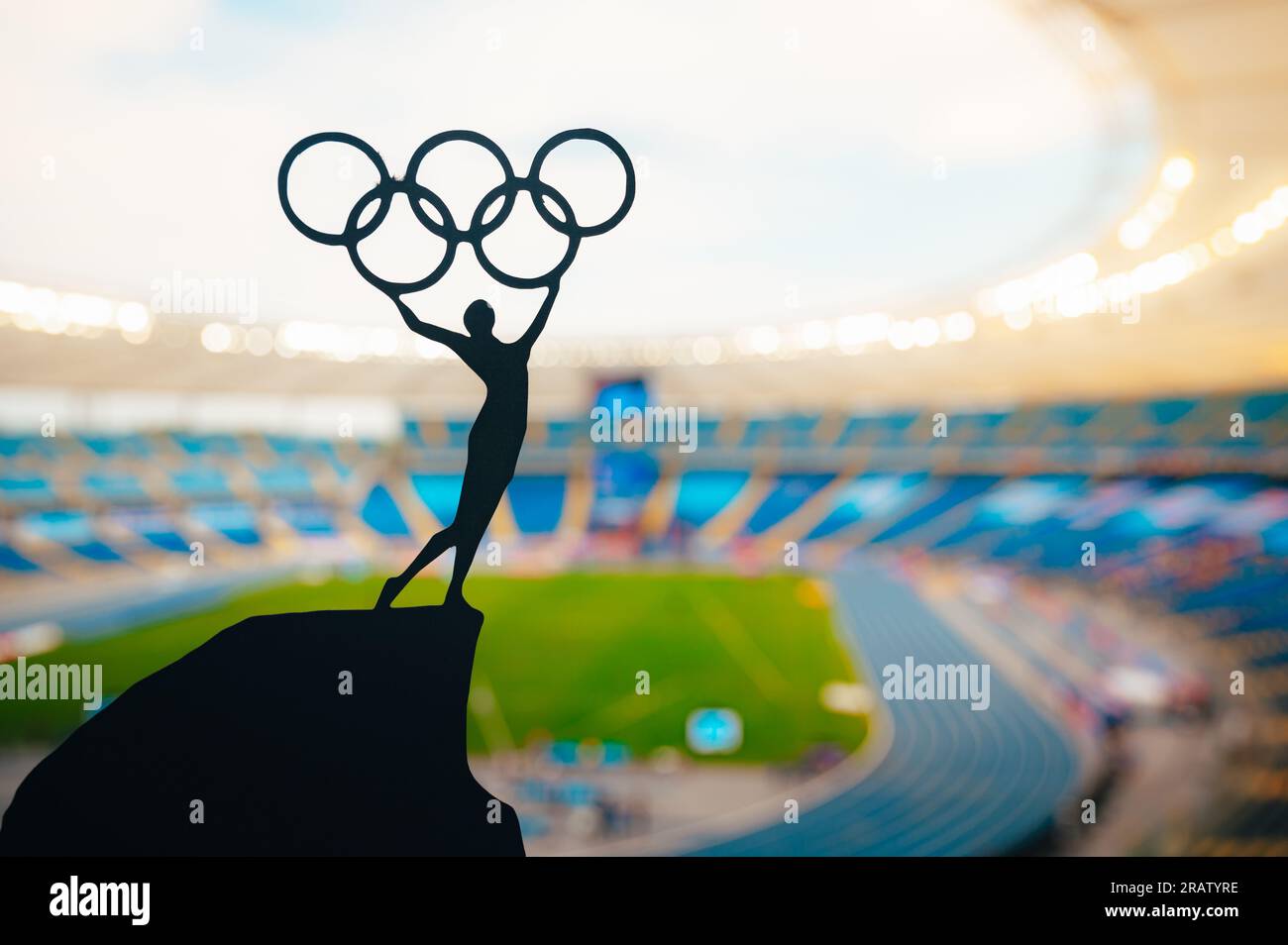 PARIS, FRANKREICH, 7. JULI 2023: Statue der Sportlerin, die über dem olympischen Kreis steht. Modernes Olympiastadion im Hintergrund. Sportfoto für den Sommer Stockfoto