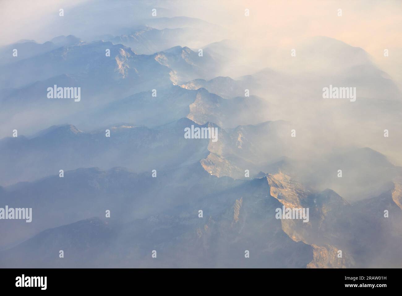 Ein Blick aus der Vogelperspektive auf einen rauchigen Himmel mit Gebirgskämmen. Stockfoto