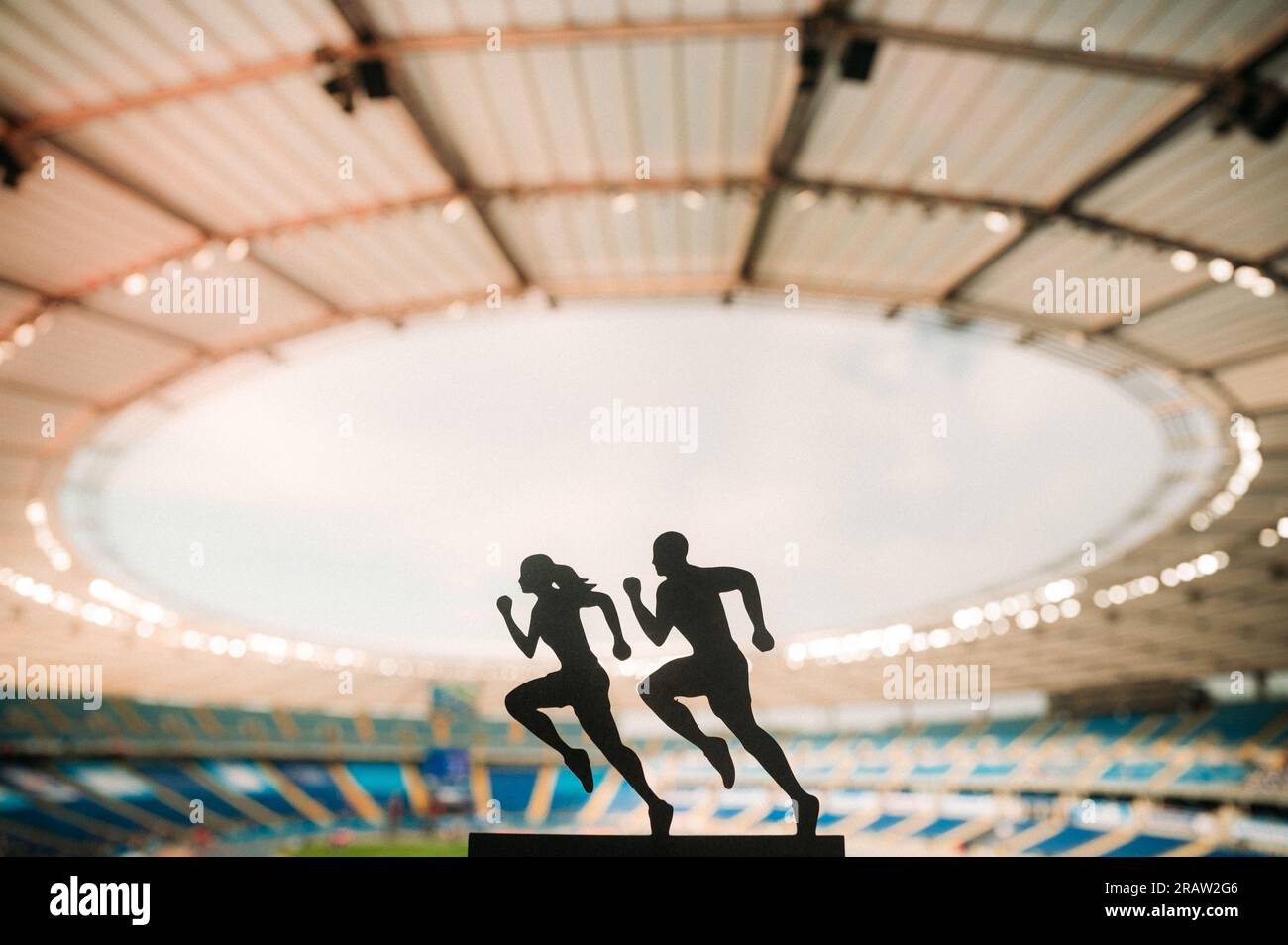 Die Silhouetten männlicher und weiblicher Läufer zeigen Widerstandsfähigkeit und Einheit und beleben ein modernes Sportstadion. Stockfoto