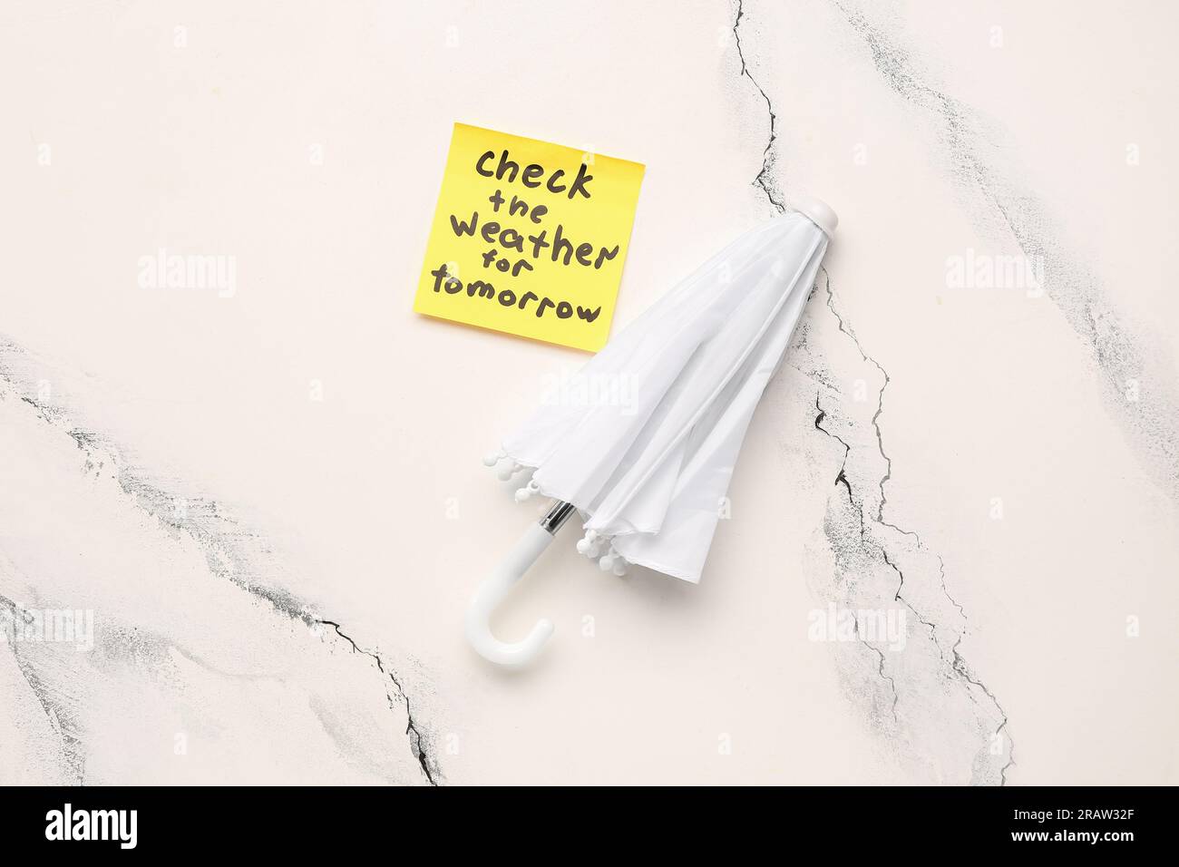 Haftnotiz mit Text CHECK DAS WETTER FÜR MORGEN und Regenschirm auf Grunge Hintergrund Stockfoto