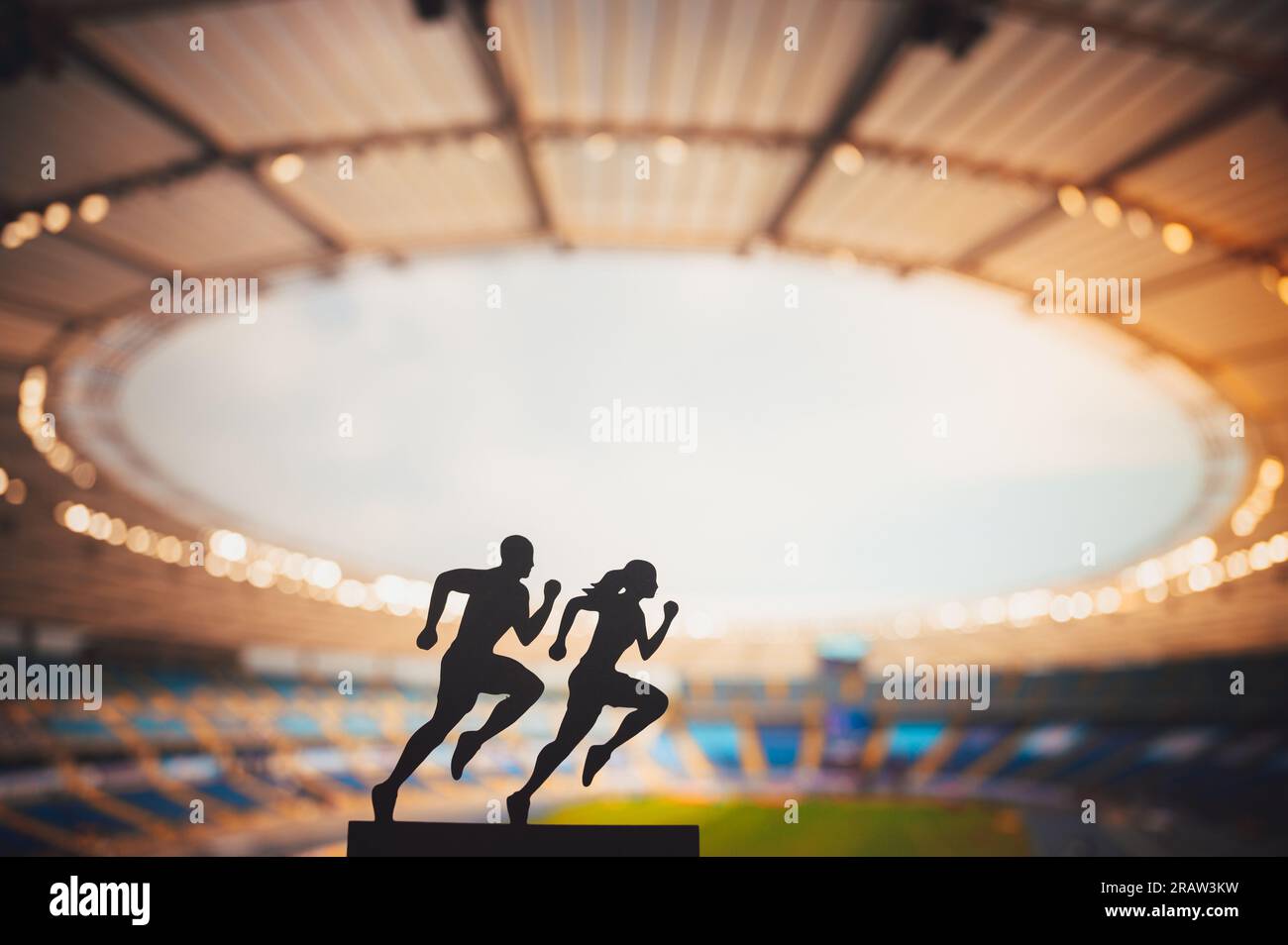 Gemeinsam nach Größe streben: Die Silhouetten männlicher und weiblicher Läufer setzen Grenzen und inspirieren sich gegenseitig in einem modernen Sportstadion. Stockfoto