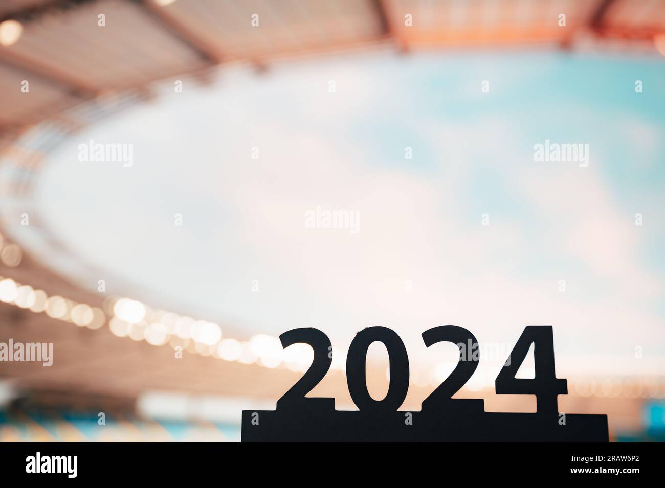 Die Silhouette des „2024“-Schriftzugs inspiriert zum Beginn des Sportjahres und führt zu den Sommerspielen in Paris. Modernes Stadion im Hintergrund. Stockfoto