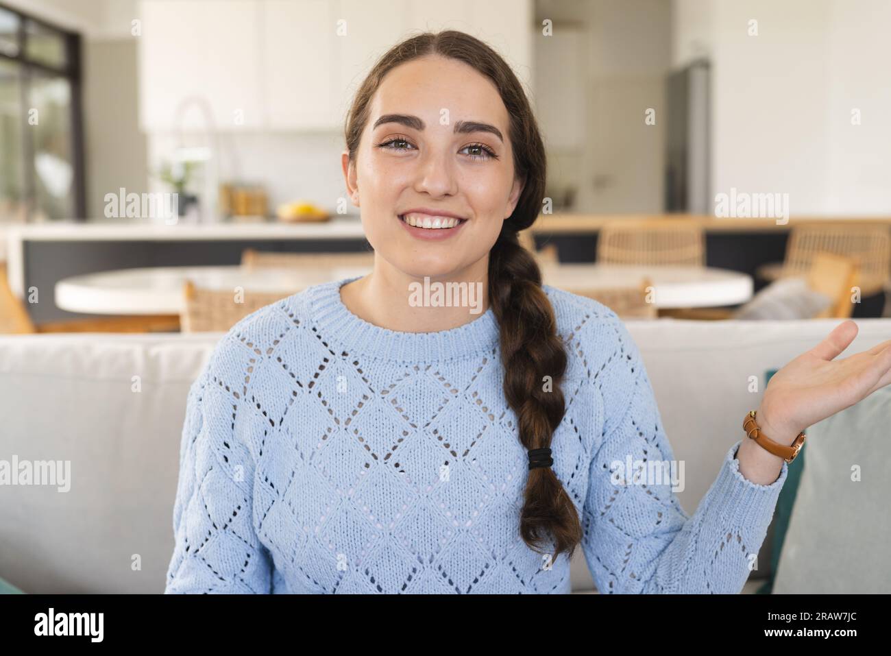 Porträt einer glücklichen Kaukasierin, die Videoanrufe mit Gesten macht und zu Hause einen blauen Pullover trägt Stockfoto