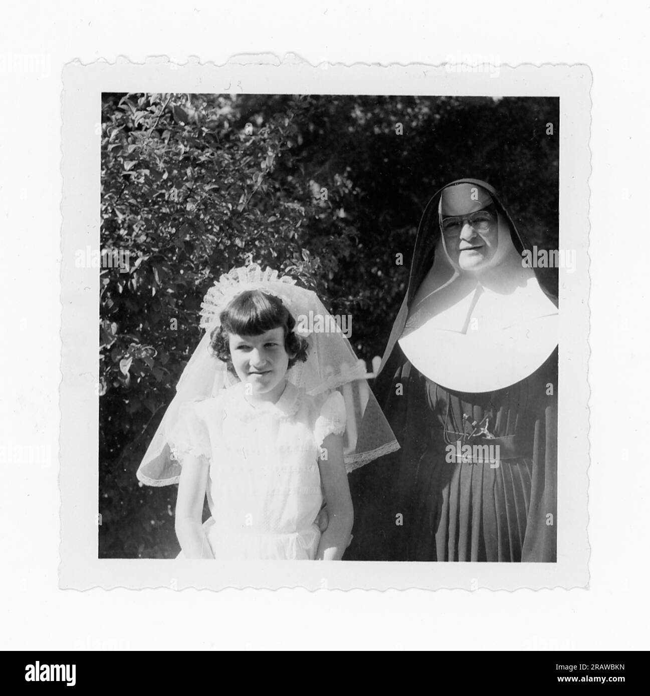 Das junge Mädchen feiert ihre erste Heilige Kommunion mit ihrem Lieblingslehrer, einer Nonne, USA Stockfoto