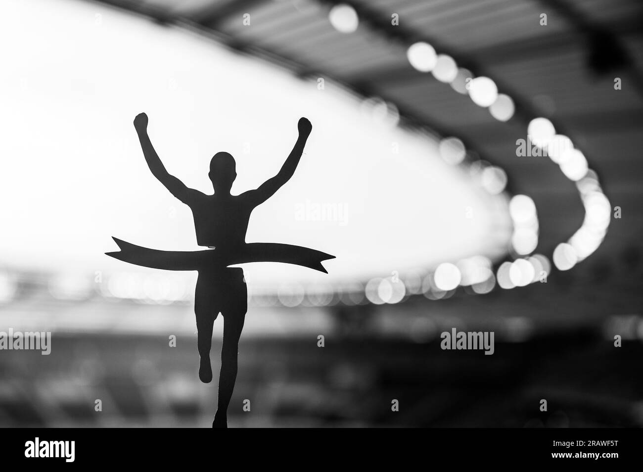 Silhouetted Runner gewinnt den Sieg im modernen Athletics Stadium. Ein inspirierender Moment für den Leichtathletikwettbewerb. Schwarzweißfoto für Sommerveranstaltung Stockfoto