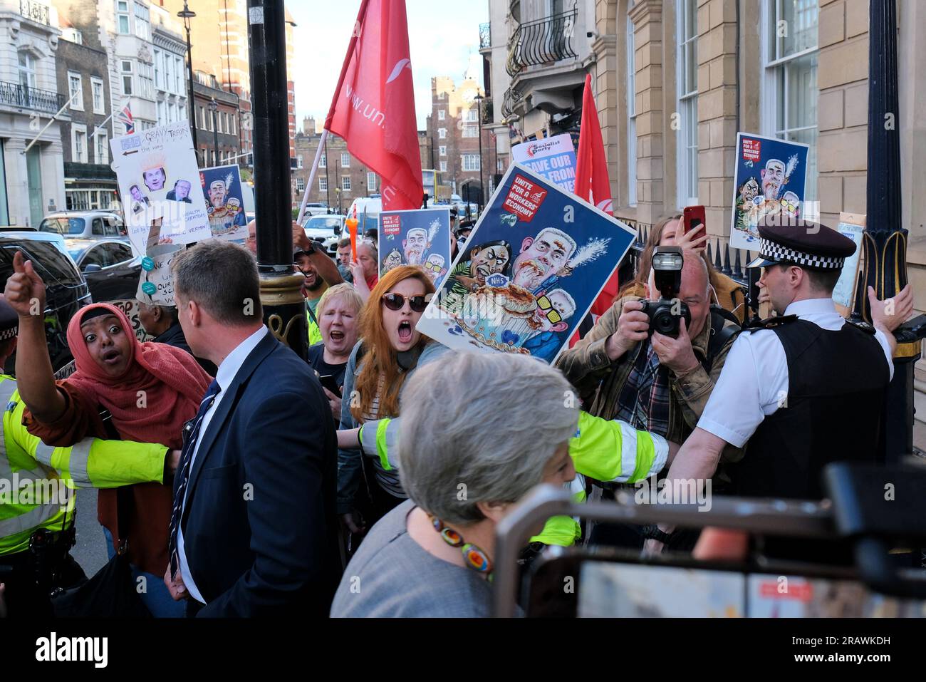 London, Großbritannien. 5. Juli 2023. Die ehemalige Ministerpräsidentin Theresa May sieht sich damit konfrontiert, dass die Union-Mitglieder im Vorfeld eines NHS-Abendessens der Konservativen Partei, bei dem der 75. Jahrestag ihrer Gründung begangen wird, gegen den Carlton Club protestieren, der ausschließlich Mitgliedern außerhalb des Clubs steht. Die Pro-NHS-Demonstranten argumentieren, dass die chronische Unterfinanzierung und die unter der Inflationsrate liegende Bezahlung zu einer Rekordzahl von freien Stellen und einem dramatischen Zusammenbruch der Patientendienste geführt haben. Kredit: Elfte Stunde Fotografie/Alamy Live News Stockfoto