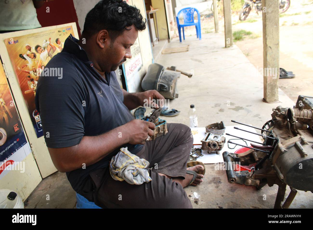 Der Mechaniker repariert ein Motorrad. Ein Mann arbeitet als Mechaniker in einer Motorradwerkstatt vor Ort. Odisha, Indien. Stockfoto