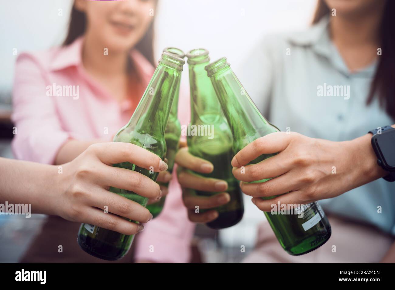 Die Hände einer jungen Frau, die beim Trinken von Bier mit der Flasche klirrt. Stockfoto