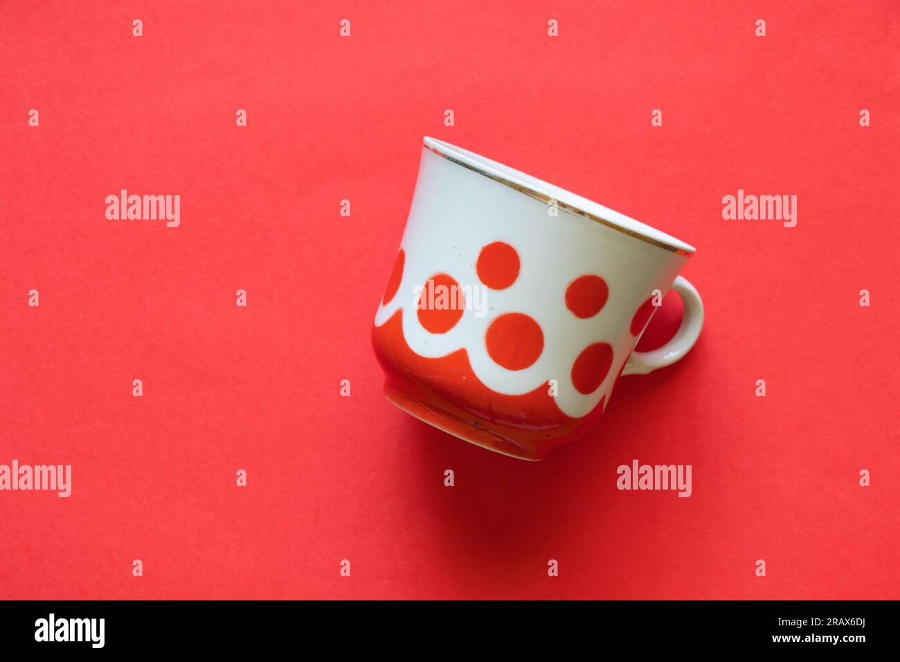Alte Tasse mit roten Punkten auf einem farbigen roten Hintergrund – Nahaufnahme Stockfoto