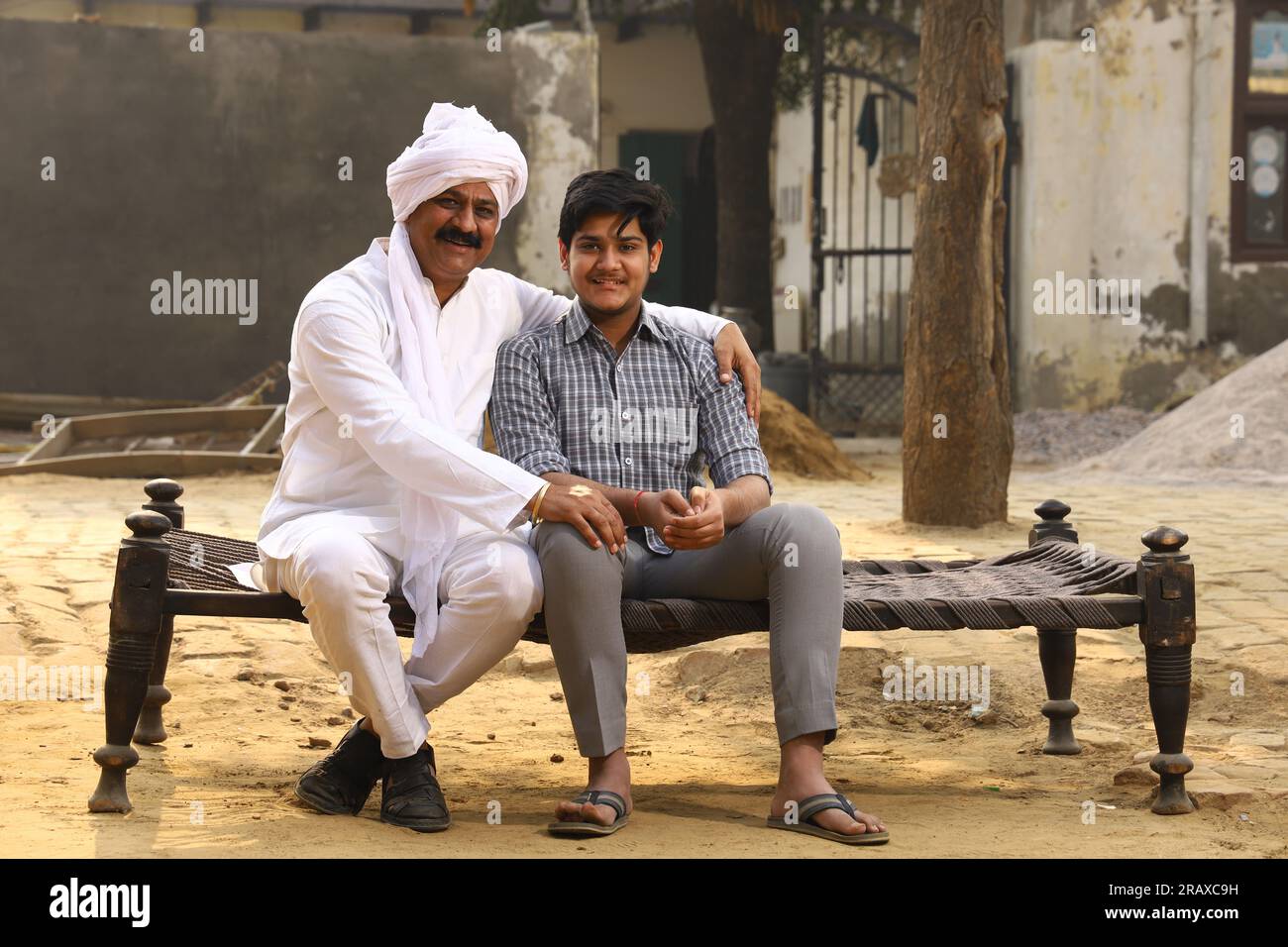 Glückliche indische Landfamilie im Dorf Aspirationsfamilie, die mit einem Bankmanager sitzt, der Daumen nach oben zeigt. Stockfoto